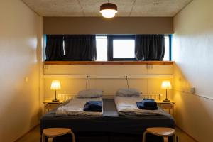 a bedroom with a bed with two chairs and two lamps at FarNorth Hostel in Bakkafjörður