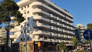a tall white building with balconies on a street at Apartamentos CH 2 in Salou