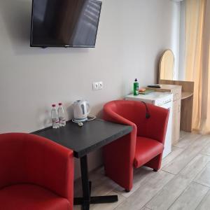 a room with two red chairs and a table and a television at EUROLINE HOTEL ODESSA in Odesa