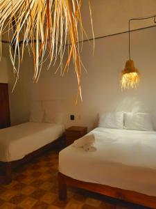 a bedroom with two beds and a pendant light at Casa Kal'i in Brisas de Zicatela