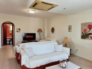 a living room with a white couch and a tv at Zoe By The Sea in Paralia Katerinis