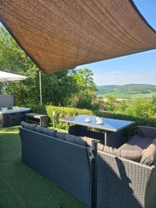a patio with a table and chairs under a large umbrella at Mecsek Szíve Glamping in Magyarszék