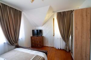 a bedroom with a bed and a tv and curtains at Casa Ursuleasa in Ciumîrna