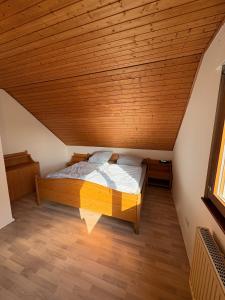 a bed in a room with a wooden ceiling at Ferienwohnung am Feistelholz in Wernberg-Köblitz