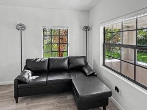 a black leather couch in a living room with two windows at Casa Arya in Howard