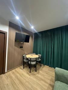 a room with a table and a tv and green curtains at MaRI&GIO in Ureki