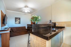 a kitchen with a counter top and a living room at Souza Apart 1 - Apartamentos completos com muito aconchego in São Thomé das Letras