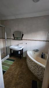 a bathroom with a bath tub and a sink at Olympia GuestHouse in Kempton Park +46 photos