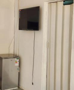 a television hanging on a wall next to a refrigerator at Olympia GuestHouse in Kempton Park