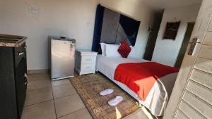 a small bedroom with a bed and a refrigerator at Olympia GuestHouse in Kempton Park