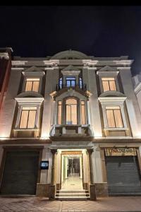 a large white building with a door at night at Hotel NASS del Sur in Cuenca