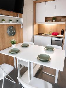 a white kitchen with a white table and chairs at Hiška Gaia- pool tickets included in Brežice