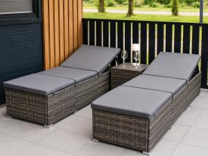 two cushioned benches on a porch with a table at Hiška Gaia- pool tickets included in Brežice