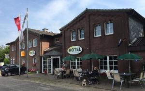 a woman sitting at a table in front of a hotel at Hotel Zur Buche in Bockhorn