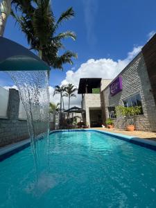 a swimming pool with a fountain in front of a building at Suíte Monstros SA - Pousada Castelo do Luar in Penha