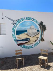 a mural of a beach with a boat and a palm tree at Les jardins de Sara in Mellita