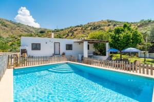a villa with a swimming pool in front of a house at La Encina in Lanjarón