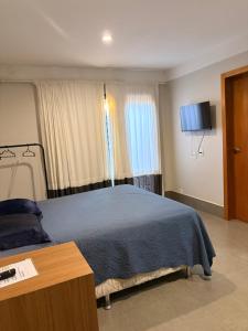 a bedroom with a blue bed and a television at Studio Central IV in Cascavel