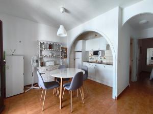 a kitchen and dining room with a table and chairs at Apartamentos Xoroi in Cala en Porter