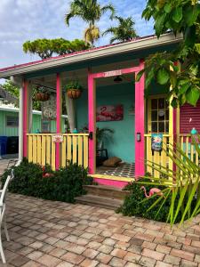 a pink and green house with a porch at Coastal Bungalows--The Flamingo Bungalow in Fort Lauderdale