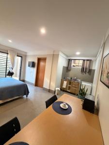 a room with a bed and a wooden table with chairs at Studio Central IV in Cascavel +3 photos