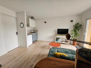 a living room with a couch and a kitchen at Cottage Fonsorbes RDC Maison in Fonsorbes