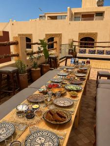 a long wooden table with plates of food on it at Kymata Surf Morocco in Agadir