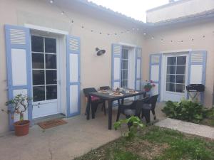 a table and chairs on a patio with blue doors at Le Gite Boho in Vendeuvre-du-Poitou