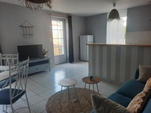 a living room with a blue couch and a kitchen at Le Gite Boho in Vendeuvre-du-Poitou