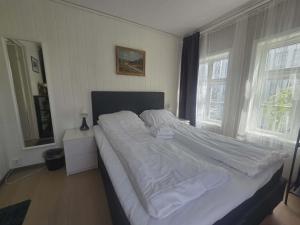 a large bed in a bedroom with two windows at Stavangerliving in Stavanger