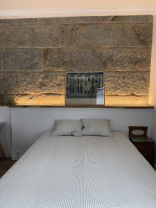 a bed in a bedroom with a brick wall at Casa Plaza do Millo in Celanova