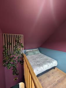 a bedroom with a bed and a purple wall at Le Boudoir d'Héloïse in Breux Jouy