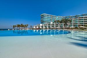a hotel with a swimming pool in front of a building at Beachfront Duplex with Multiple Pools - Beachclub in Nuevo Vallarta