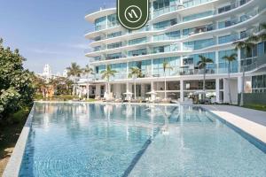 a swimming pool in front of a large building at New 2BR APT - Beach Access - Pool - GYM - Jacuzzi in Nuevo Vallarta