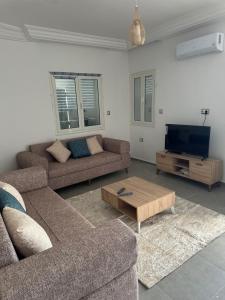 a living room with two couches and a flat screen tv at Les jardins de Sara in Mellita