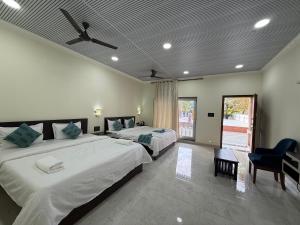 a bedroom with two beds and a chair at Baga Beach Palm Cottage in Calangute +51 photos