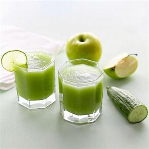 two glasses of green juice with an apple and a cucumber at Velora Stays - Nr Airport & World trade center in Pune