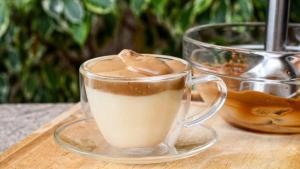 a glass cup of coffee on a wooden table at Velora Stays - Nr Airport & World trade center in Pune