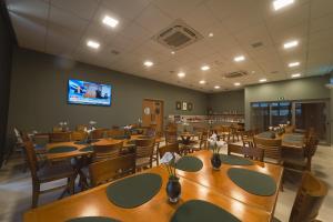 a restaurant with tables and chairs and a flat screen tv at Mantra Hotel in Feliz Natal