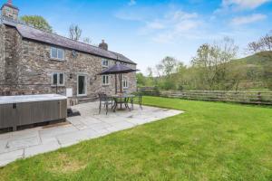a stone house with a patio and a table with an umbrella at 2 Bed in Abergele oc-88974 in Llanfair Talhaiarn
