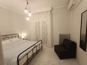 a bedroom with a bed and a black chair at Elenis Garden View Apartment in Perea