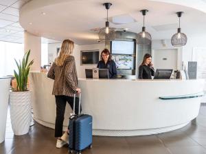 a woman with a suitcase standing at a counter at Novotel Suites Marseille Centre Euromed in Marseille +120 photos