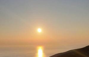 a sunrise over the water with the sun in the sky at GIATRELOS HOUSE "near the shipwreck Zakynthos" in Volímai