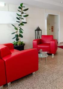 a lobby with red chairs and a potted plant at Grunau Hotel in Bayreuth