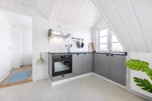 a kitchen with gray cabinets and a stove at Høloftet - Charming Vacation Apartment On The 1St Floor Of Hawbakken in Hjørring