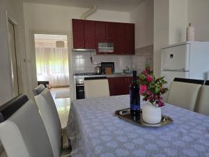 a kitchen with a table with a bottle of wine and flowers at Apartman Humac in Otočac