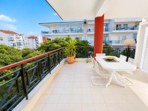 a balcony with a white table and chairs on a building at Elenis Garden View Apartment in Perea