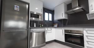 une cuisine avec un réfrigérateur en acier inoxydable et un micro-ondes dans l'établissement Oasis beach, à Playas de Orihuela