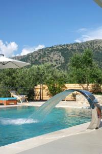 a water fountain in a pool with a mountain in the background at ORDAMS Villa in Himare