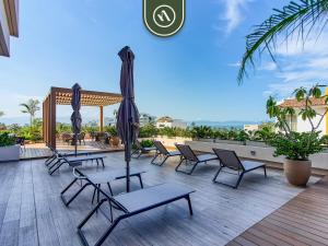 a group of chairs and umbrellas on a deck at New 1 BR Condo with Amazing Rooftop Pool - Jacuzzi in Bucerías